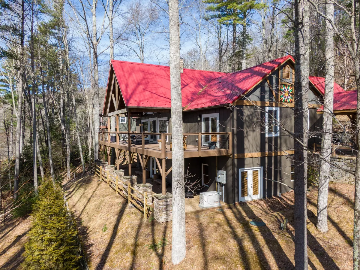 A cozy wooden deck featuring outdoor seating, large windows looking out into nature, and a splash of color on the wall. The space feels inviting for both humans and pets, ideal for outdoor lounging after a day on the trails.
