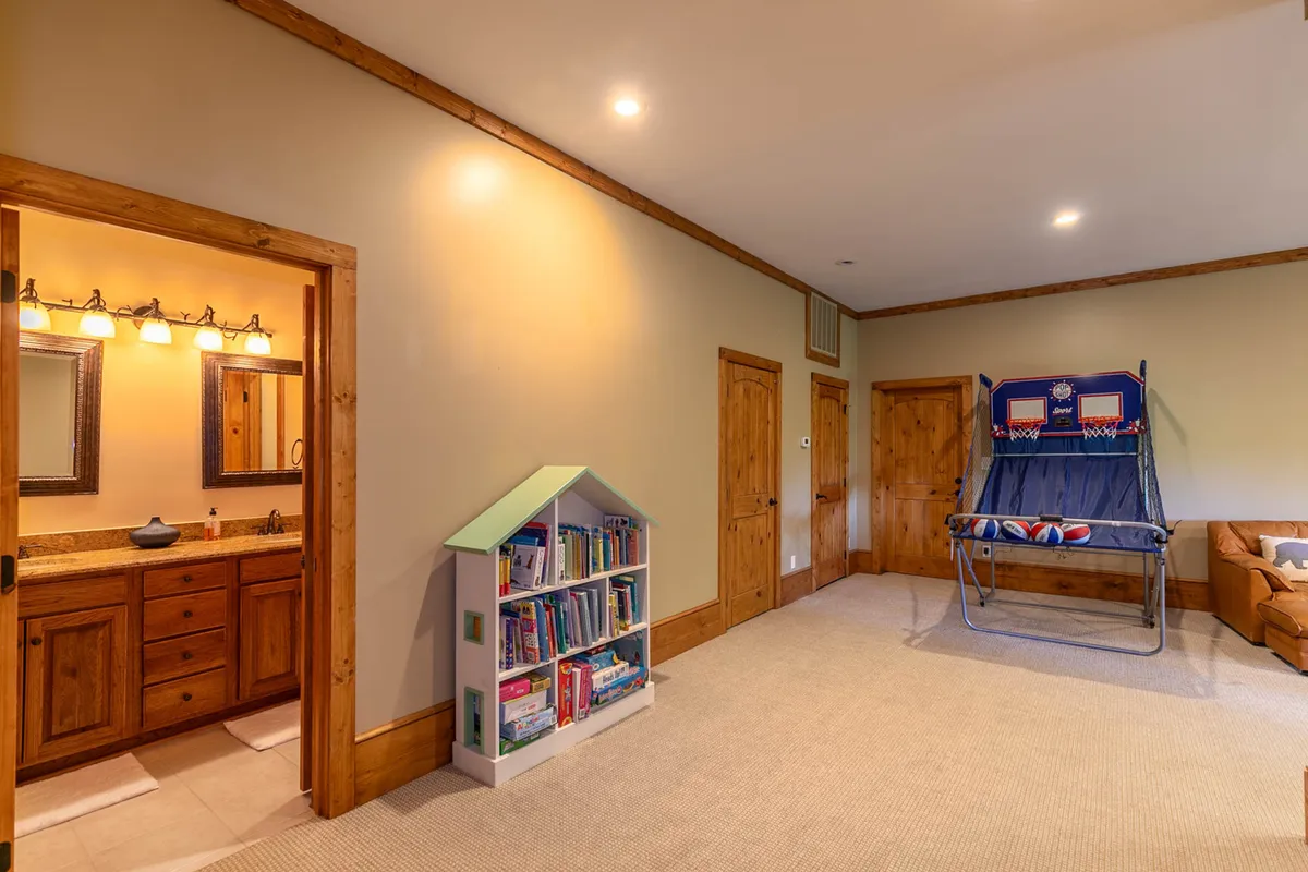A vibrant bunk room with twin-over-twin bunks, a single bed, a bookshelf, and a small vanity area. The space feels playful and accommodating, ideal for children or group sleepovers.