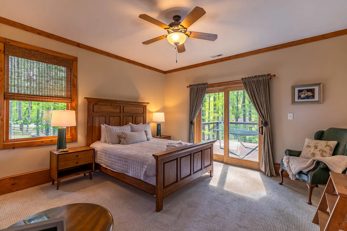 A serene bedroom featuring a plush king bed, a sliding glass door that lets in natural light, a cozy nightstand, and an inviting armchair. The tranquil setting suggests a restful atmosphere perfect for relaxation.
