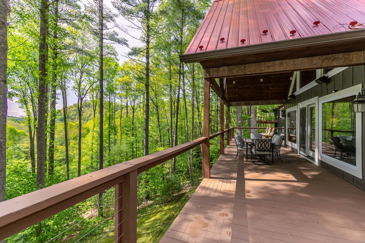 A scenic deck stretches outward with comfortable seating, inviting guests to unwind while taking in mountain views through the surrounding trees. The scene suggests quiet moments for stargazing or sipping drinks, beautifully encapsulating both community gatherings and peaceful solitude.